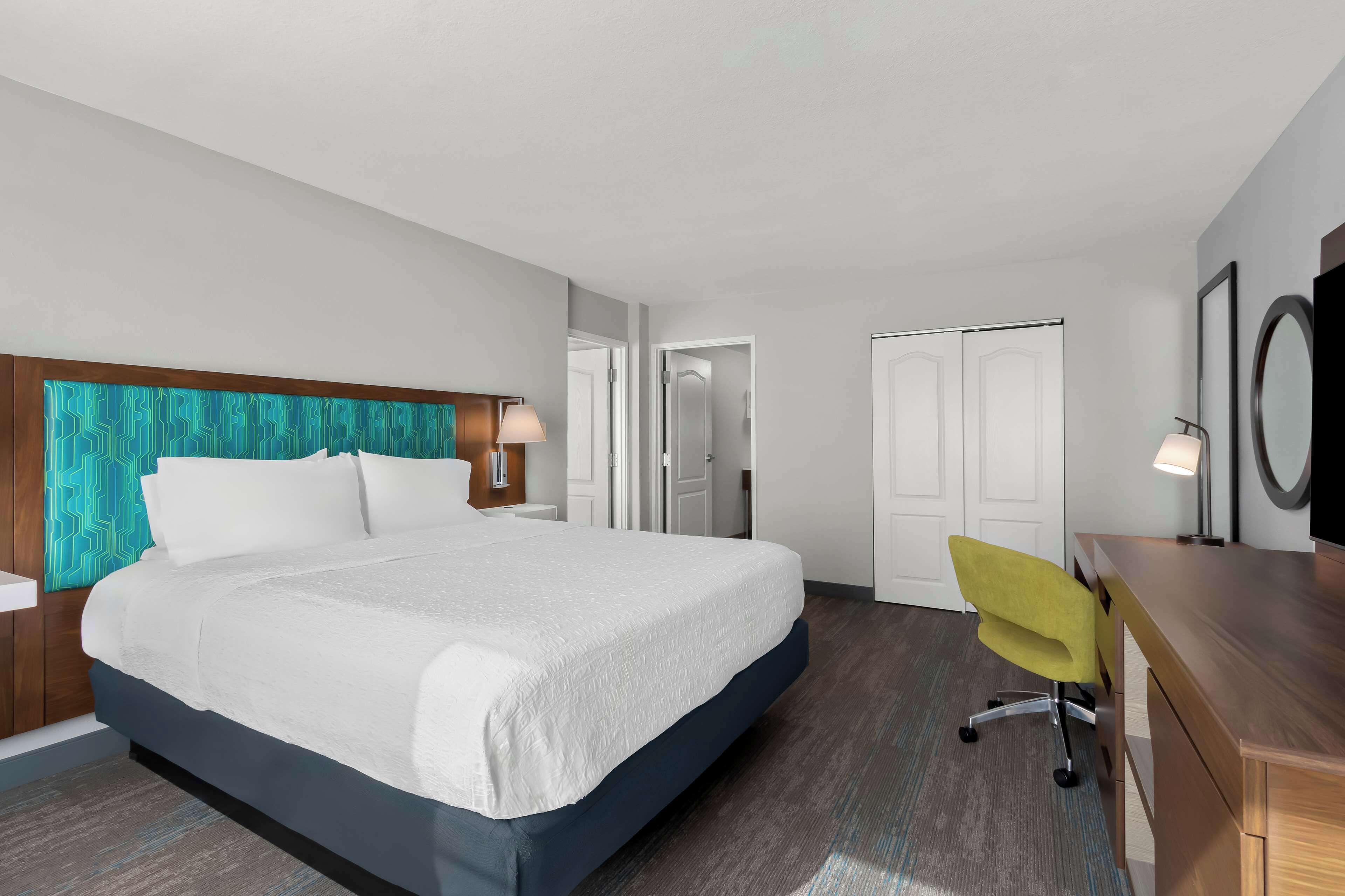 Una habitación de hotel con una cama grande, un escritorio, una silla y un armario.
