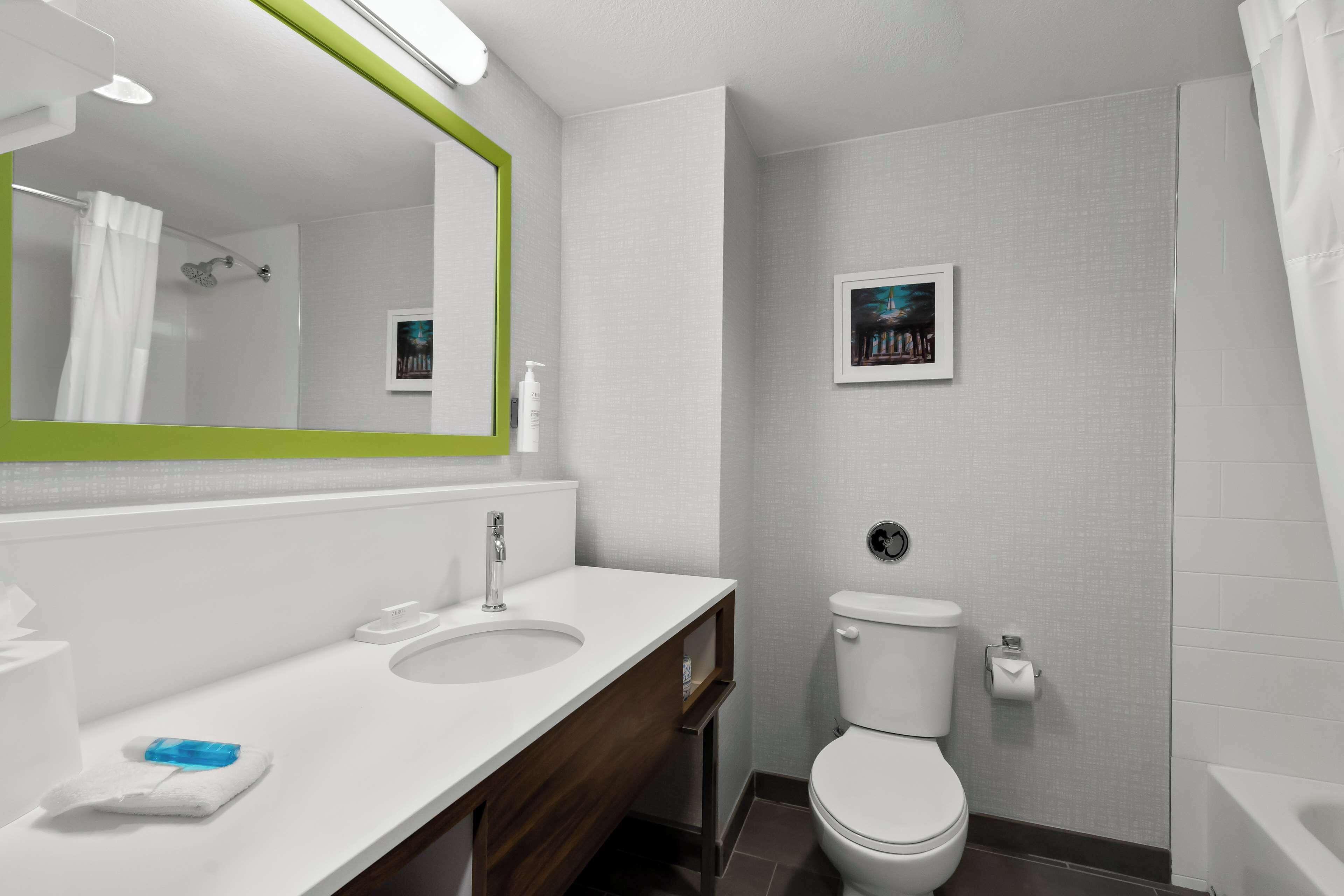 A modern bathroom with a white sink, mirror, and toilet.