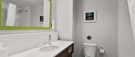 Un baño moderno con lavamanos, espejo y retrete blancos.