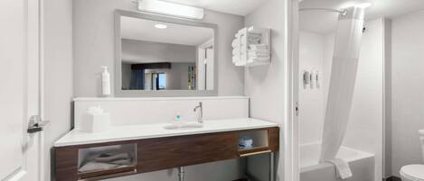 Un baño moderno con tocador blanco, un espejo grande, ducha con puerta de cristal y un inodoro.