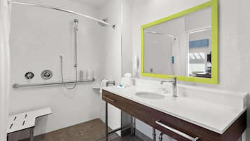 Un baño moderno con ducha, lavamanos con espejo y un perchero para toallas.