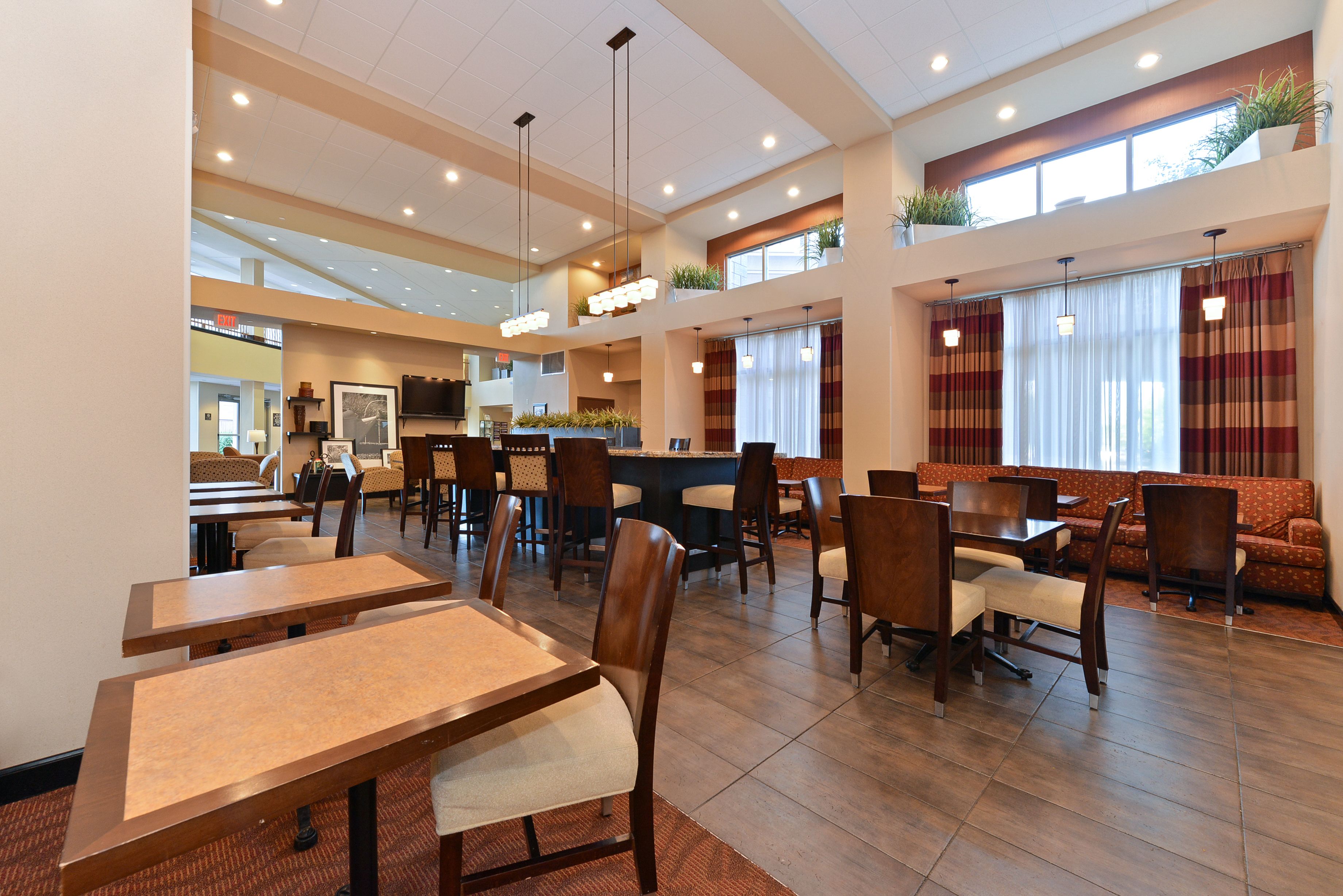 A spacious hotel lobby with multiple seating areas, including a bar and dining tables.