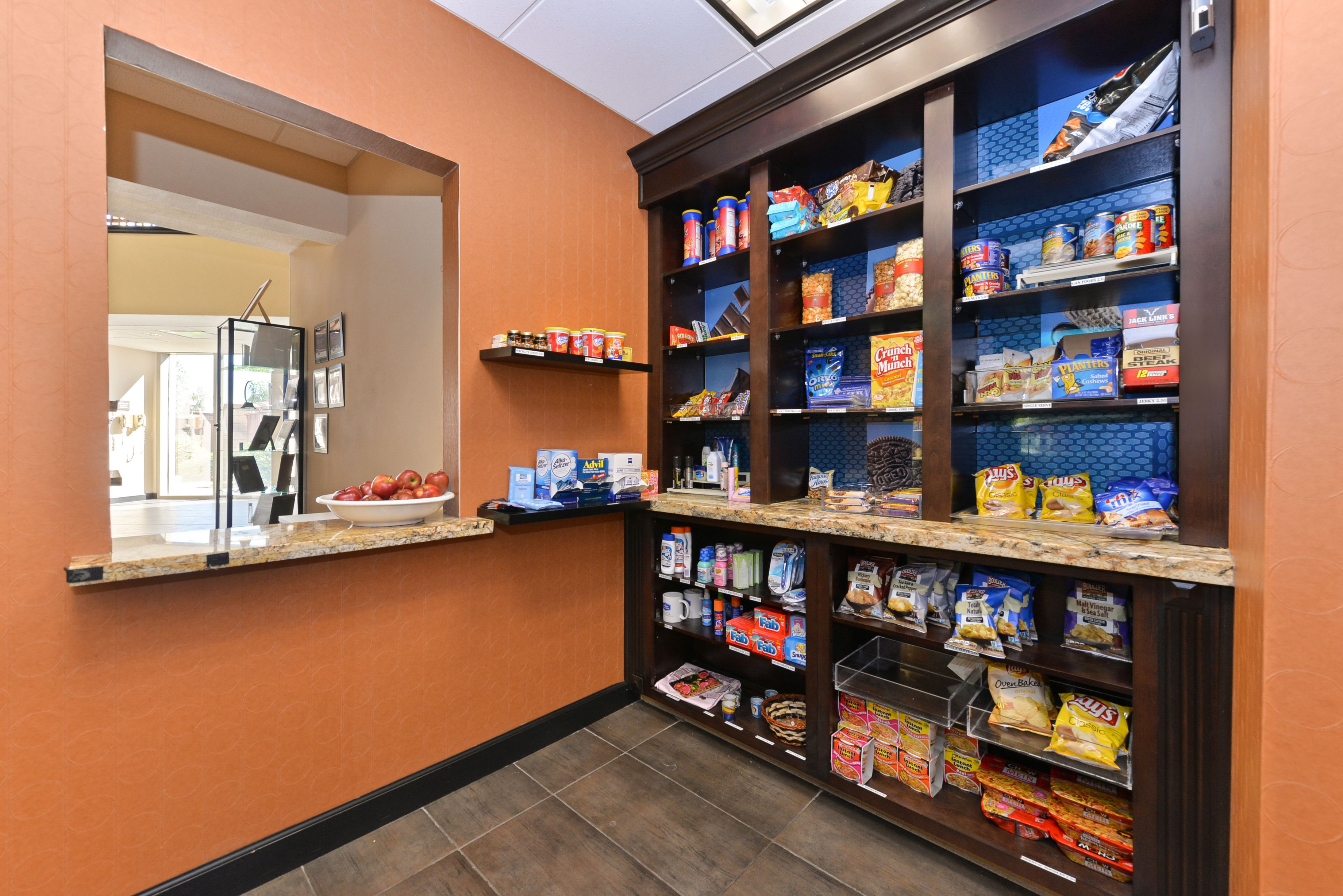 A hotel pantry with shelves stocked with snacks, beverages, and other food items.