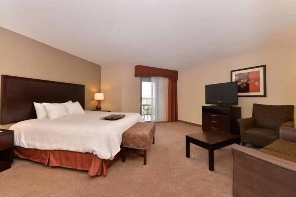 Une chambre d’hôtel équipée d’un lit, d’un bureau, d’une chaise, d’une télévision et d’une fenêtre avec des rideaux.