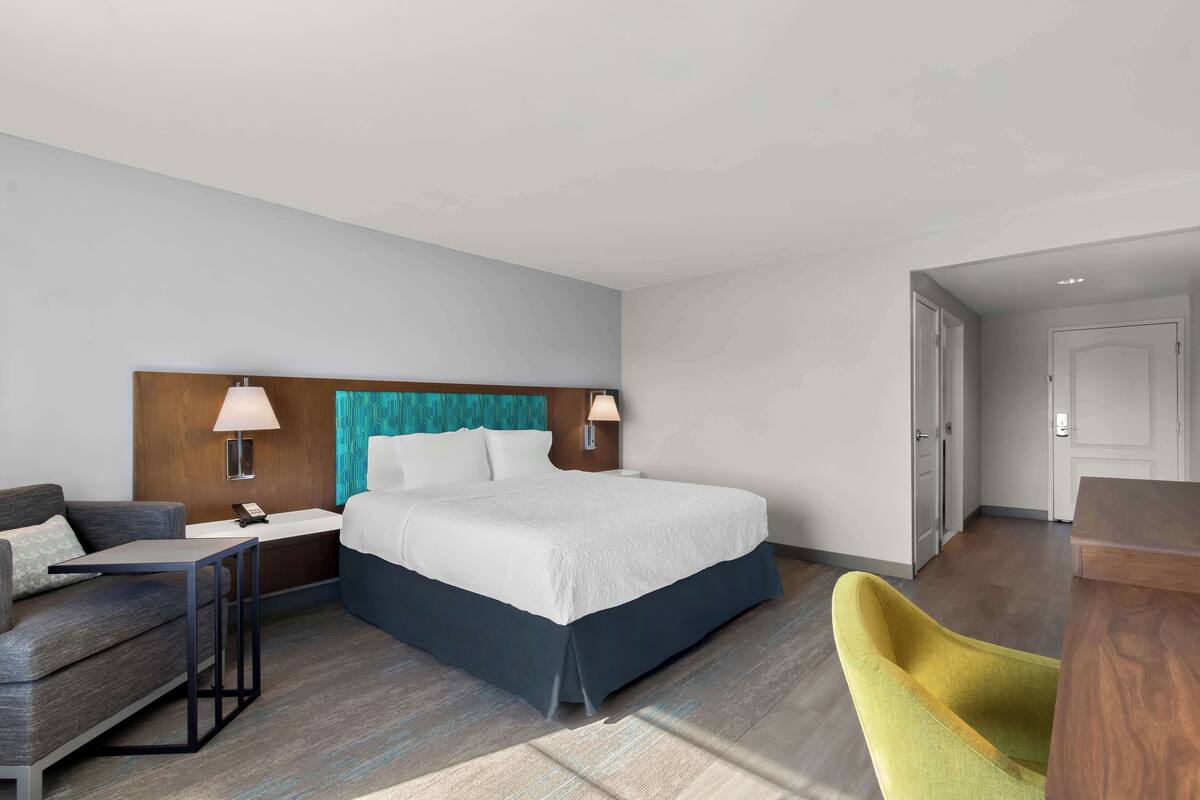Une chambre d’hôtel moderne, dotée d’un grand lit, d’un canapé, d’un bureau et d’une chaise.