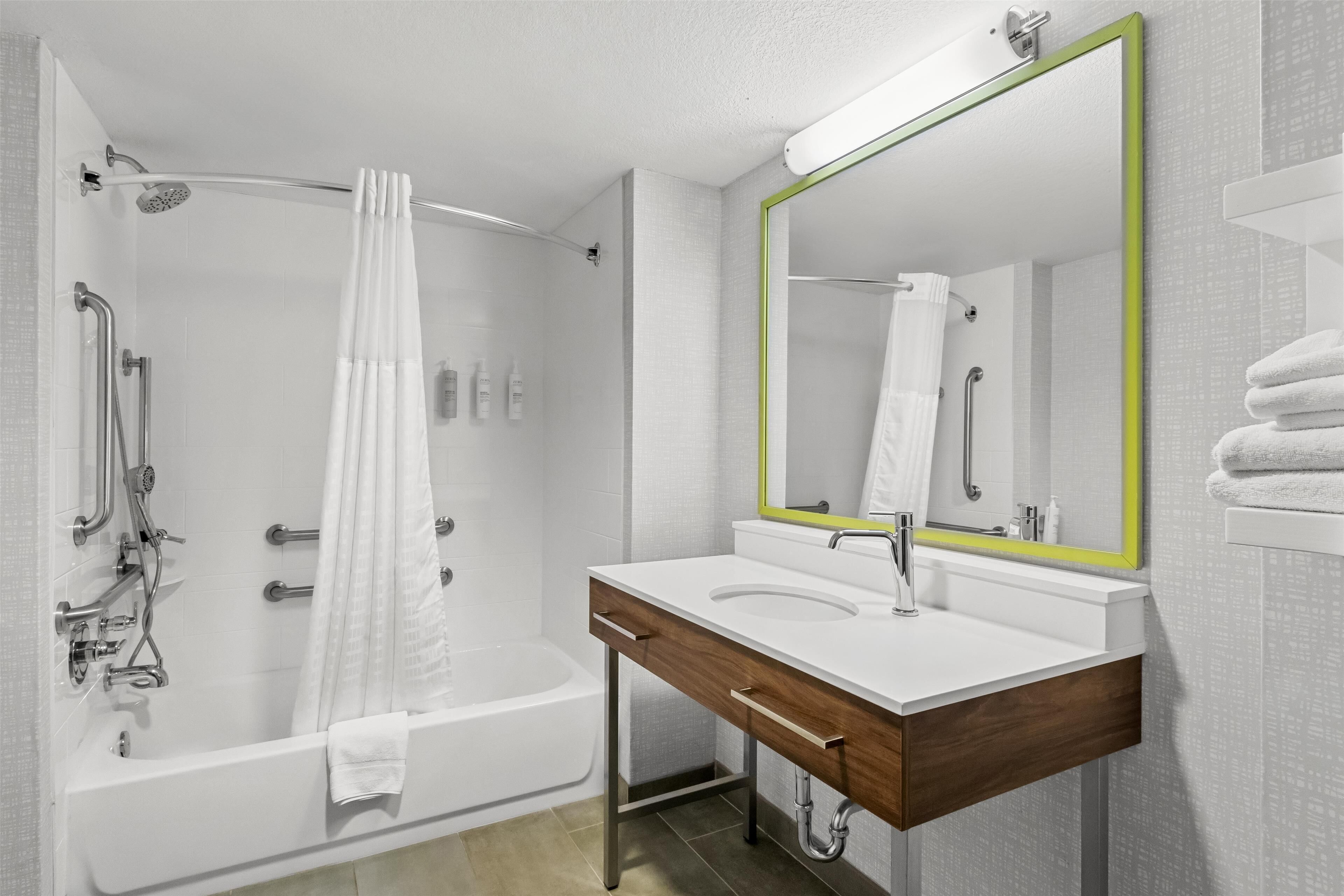 A modern bathroom with a bathtub, shower, and a vanity with a mirror.