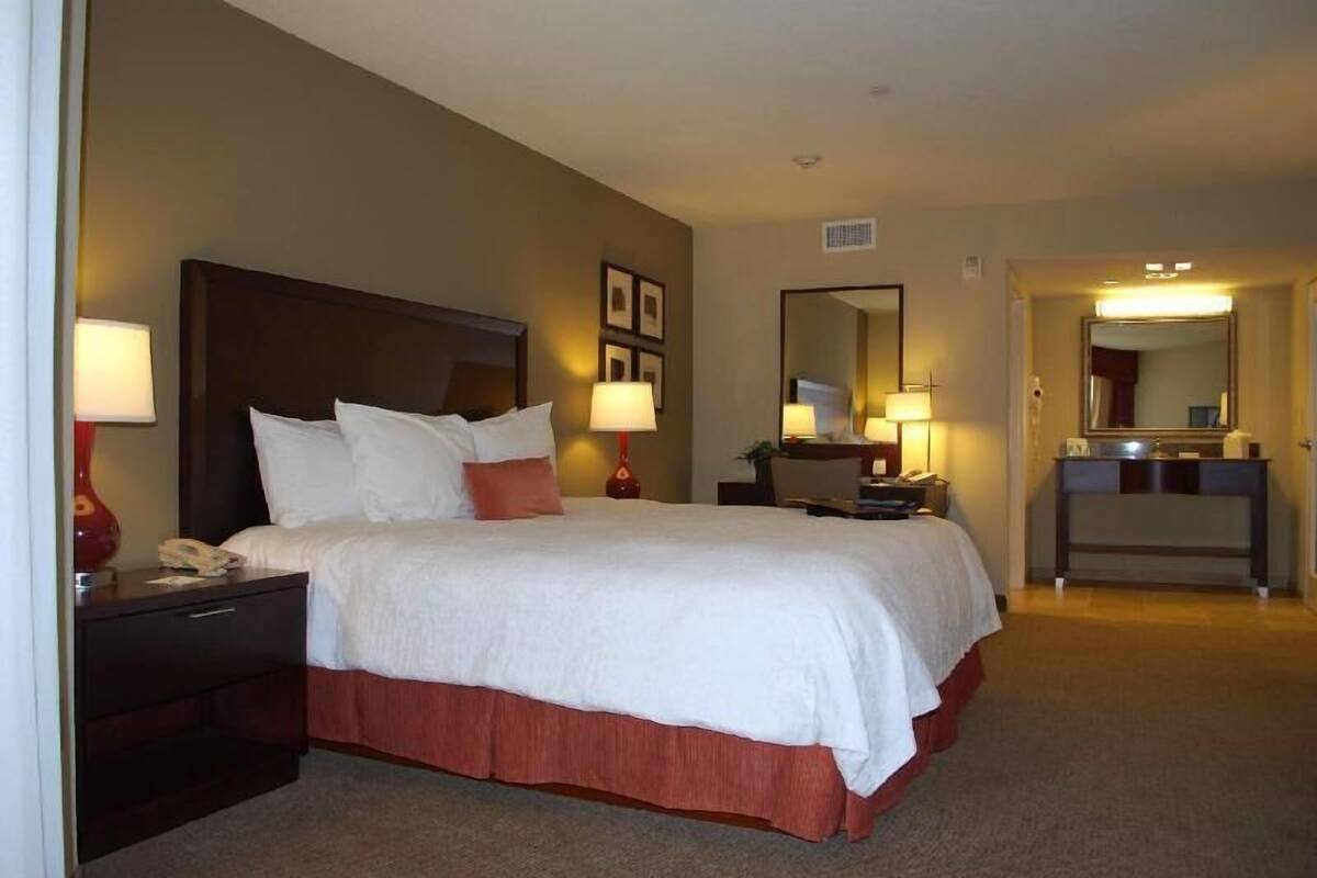 Une chambre d’hôtel comprenant un lit, des lampes de chevet, un bureau avec un miroir et un téléphone.