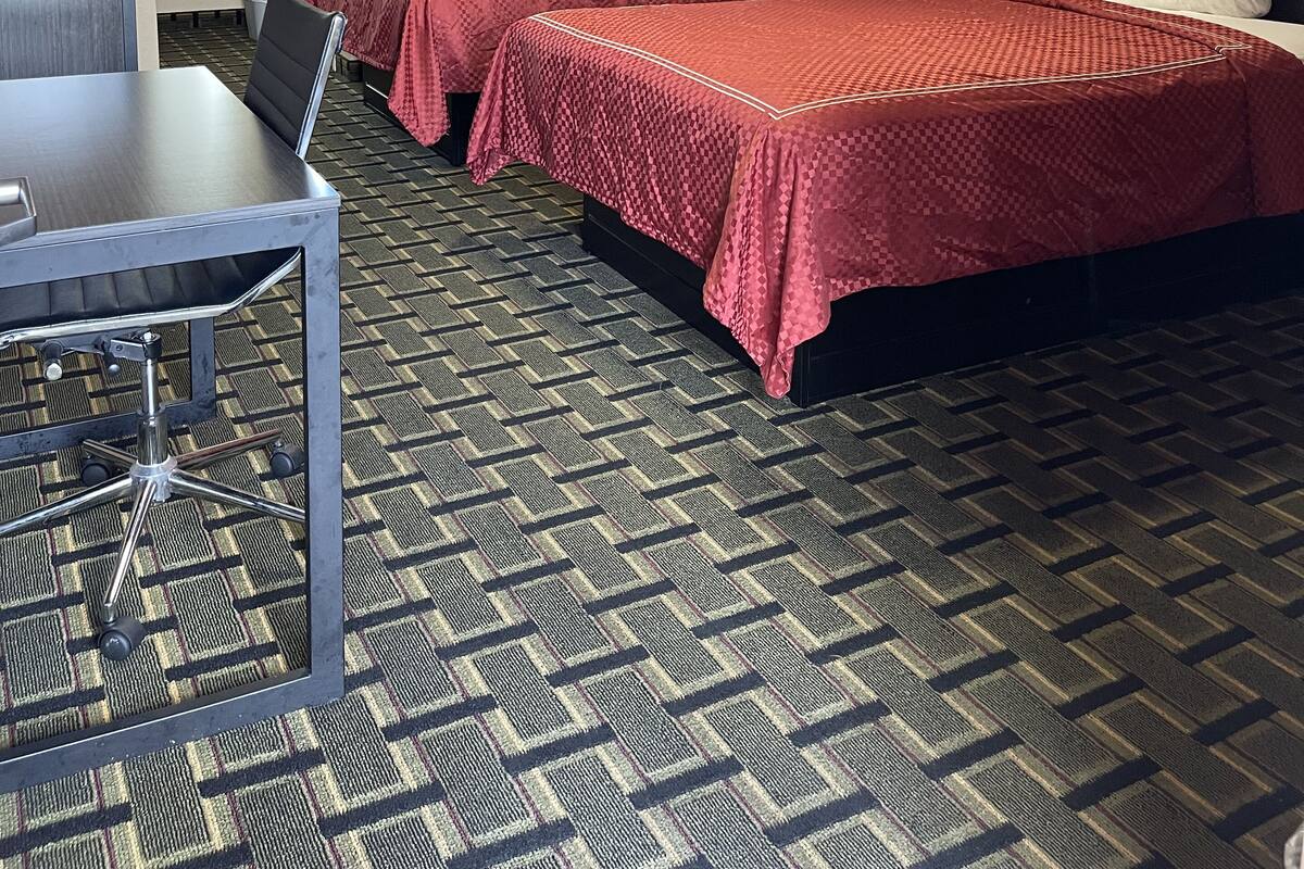 Ein Hotelzimmer mit zwei Betten, einem Schreibtisch und einem durchgegangenen Tür sichtbaren Badezimmer.
