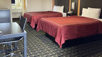 A hotel room with two beds, a desk, and a bathroom visible through an open door.