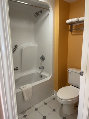 Bathroom features a bathtub with a showerhead and grab bar, alongside a toilet with a towel rack.