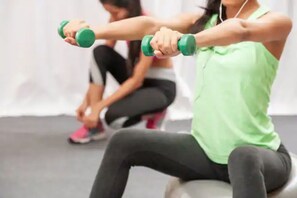 Una persona ejercitando con mancuernas en un gimnasio.