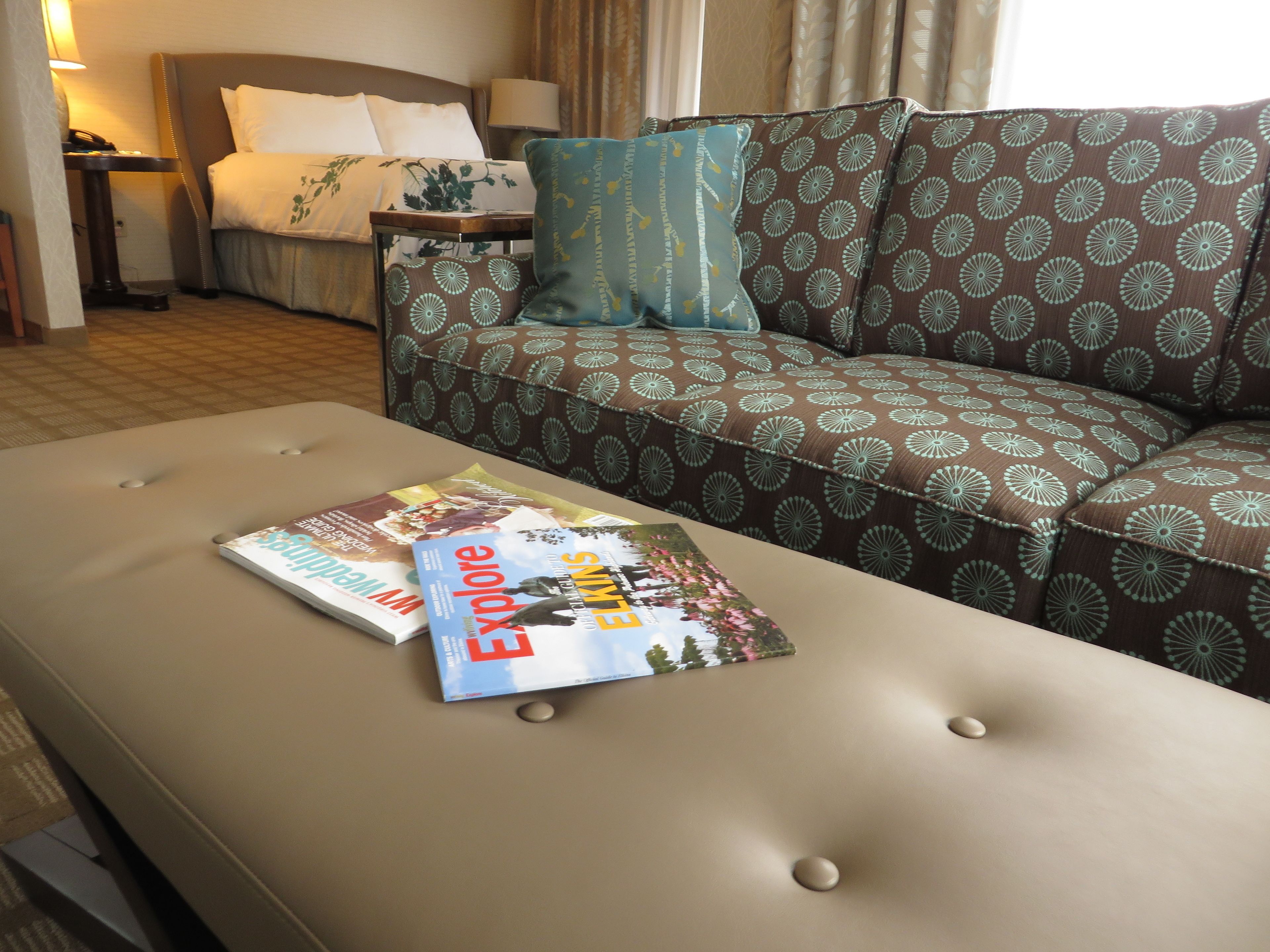 Una habitación de hotel con una cama, un sofá y una mesa con revistas.