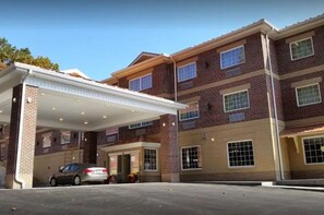 Un edificio de varios pisos con un estacionamiento techado y un automóvil dentro.