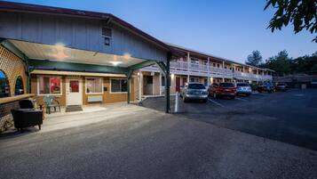 Ein Motel mit überdachtem Eingangsbereich, mehreren Parkplätzen und einer Reihe von Zimmern mit Balkonen.