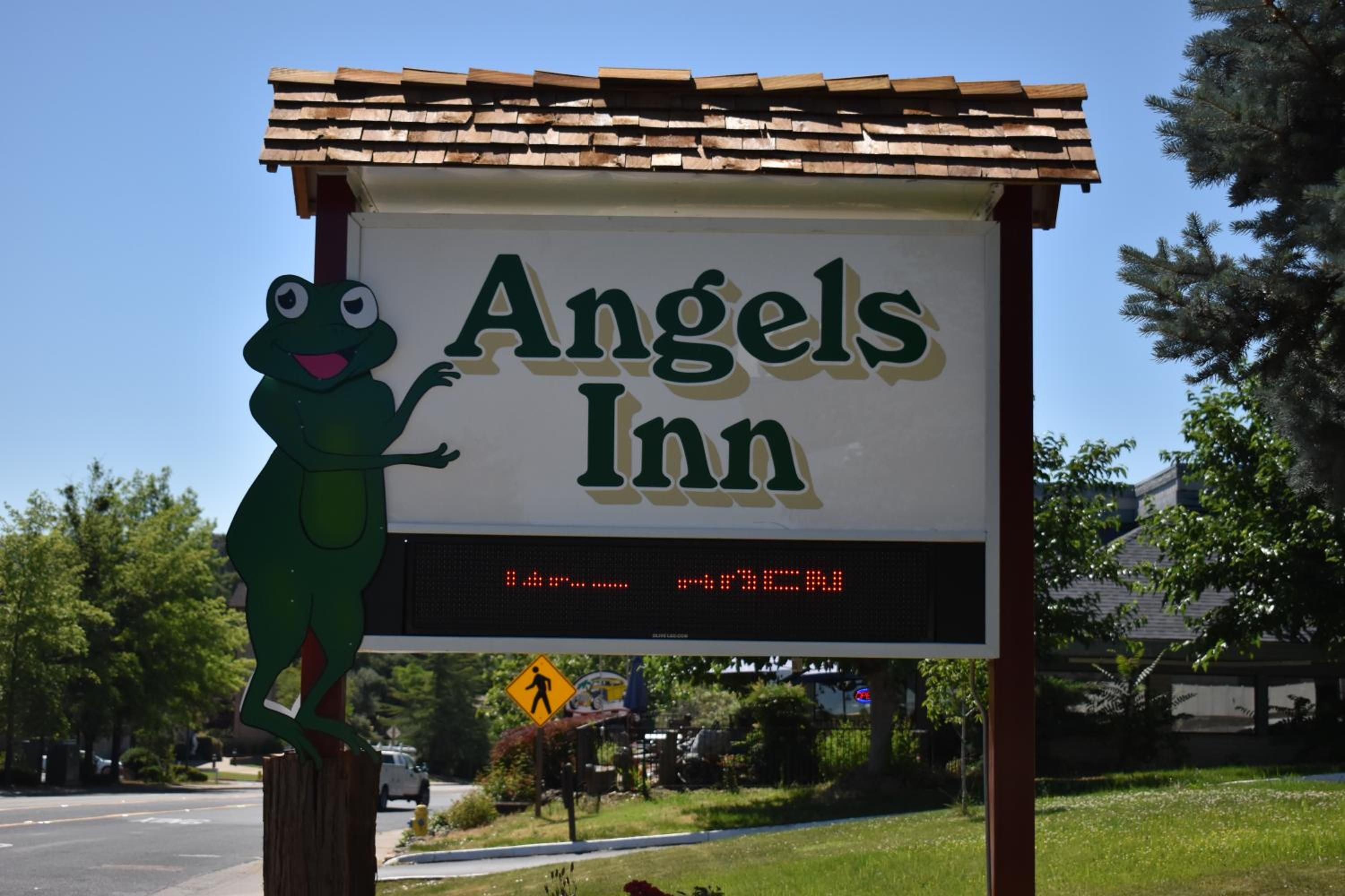 Een bord voor Angels Inn met een digitaal display en een kikker-mascotte.