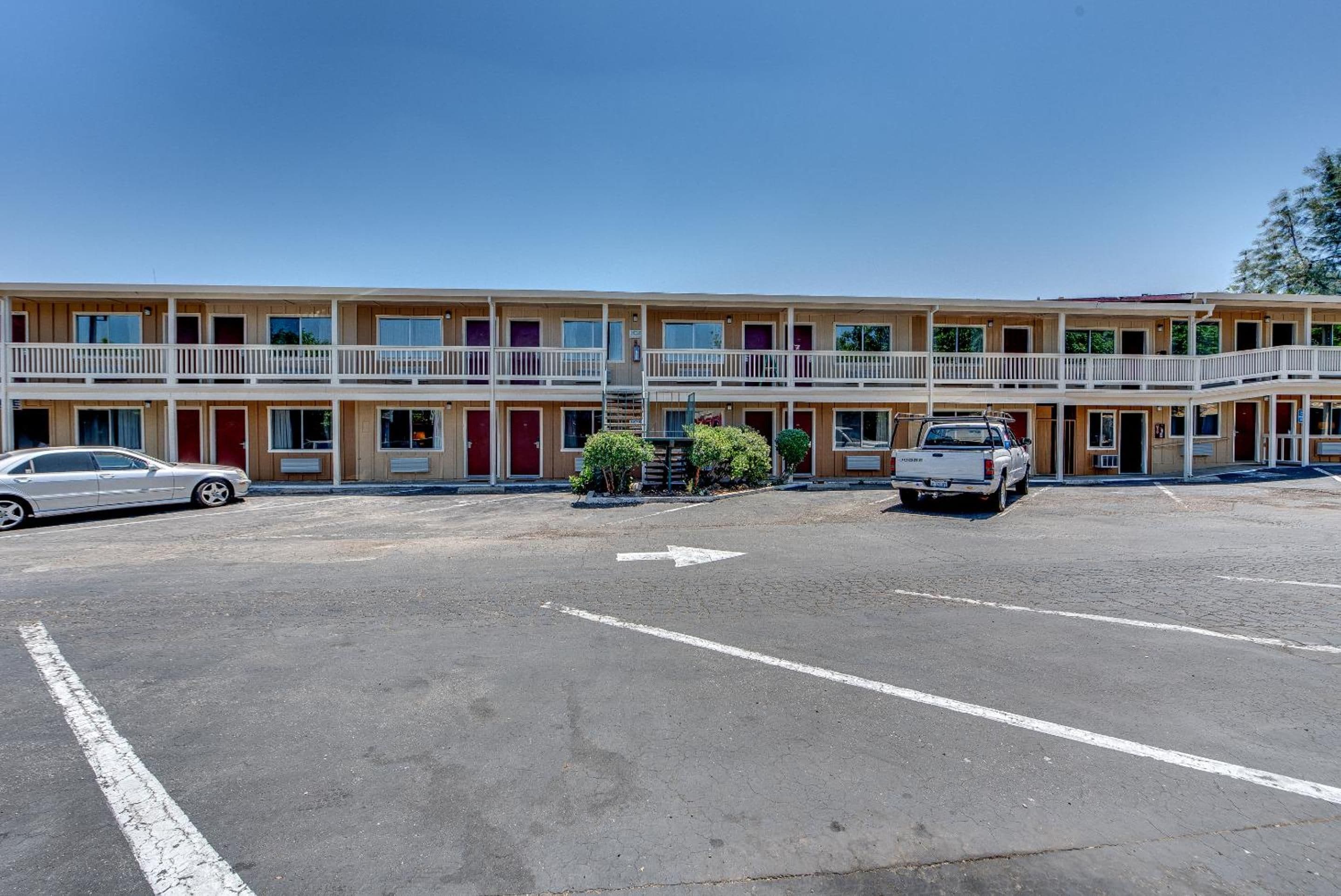 A motel with a parking lot, two-story buildings, and a white pickup truck parked in the lot.