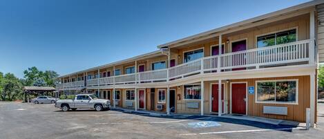 Un motel de dos pisos, con varias habitaciones y un área de estacionamiento.