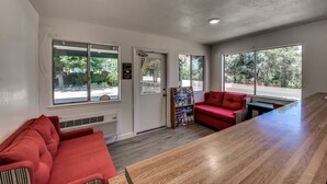 A modern interior with a wooden table, red sofas, and a bulletin board. - Angels Inn (Angels Camp)