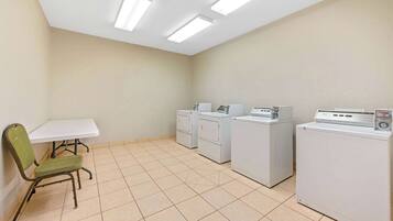 A laundry room with a table, chairs, and multiple washing machines.