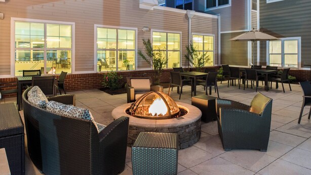 An outdoor patio with wicker furniture, a fire pit, and a brick wall. - Residence Inn by Marriott Harrisonburg (Harrisonburg)