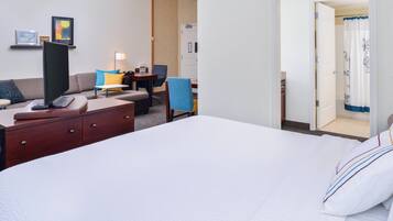 Quarto de hotel com uma cama grande, uma mesa, uma cadeira, um sofá e uma televisão.