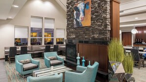 A modern lounge area with seating, a fireplace, and a view of the outside. - Residence Inn by Marriott Harrisonburg (Harrisonburg)