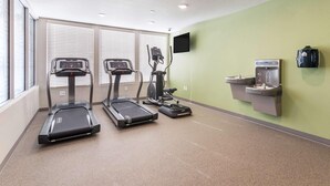 A fitness room with treadmills, a water dispenser, and a TV on the wall. - WoodSpring Suites Spartanburg - Duncan (Duncan)