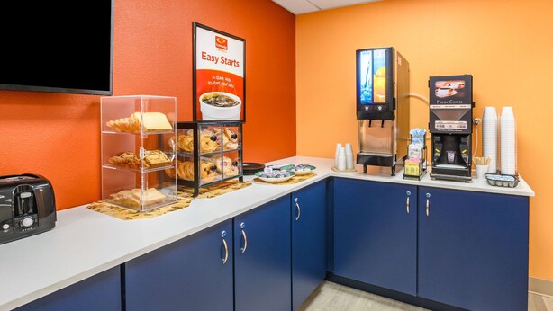 A breakfast bar with a toaster, a coffee machine, and a display case with pastries. - Econo Lodge Hammond (Hammond)