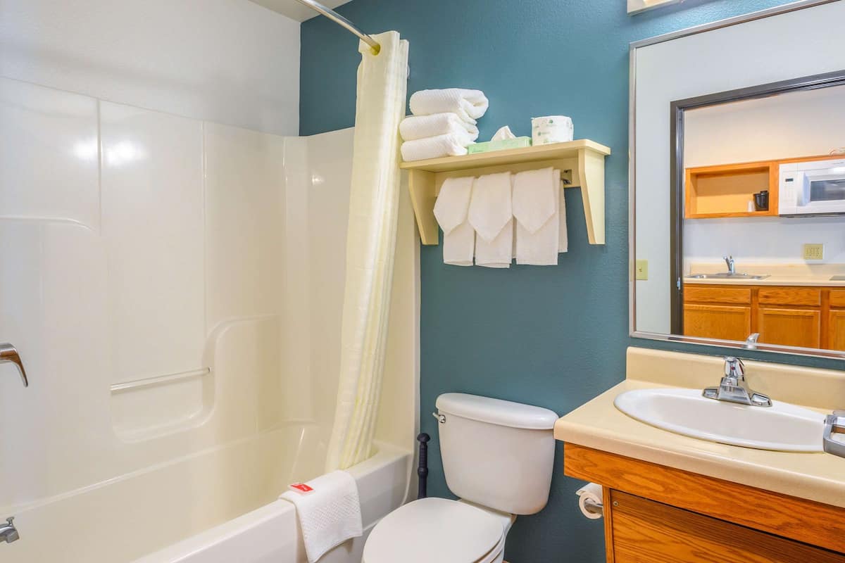 A bathroom with a bathtub, toilet, sink, and a mirror.