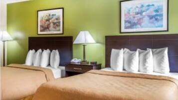 A hotel room with two beds, green walls, and artwork above the beds.