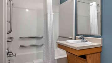 Un baño moderno con cabina de ducha de vidrio, un lavamanos blanco con mueble de madera y un espejo sobre el lavamanos.