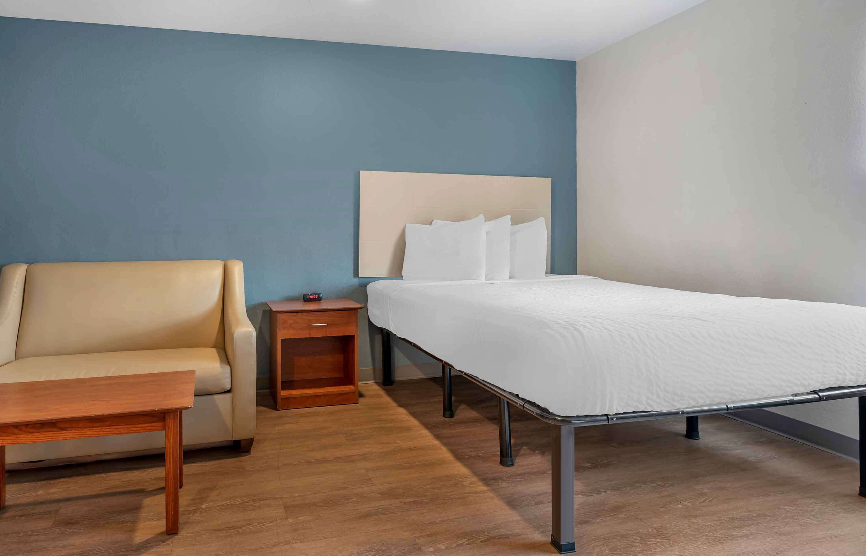 Ein Hotelzimmer mit einem Bett, einer Schlafcouch, einem Nachttisch und einem Holztisch.