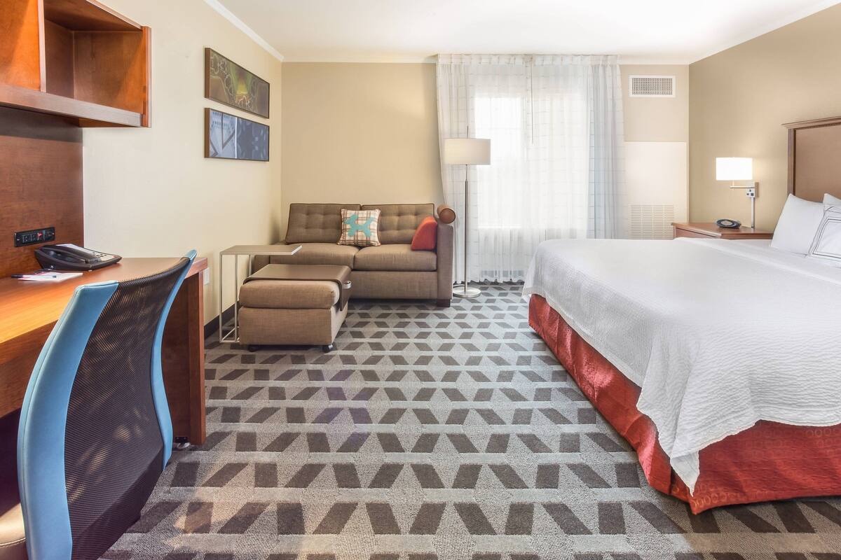 Une chambre d’hôtel comprenant un lit, un bureau avec un téléphone, un canapé et une chaise.