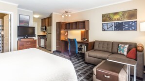 Une chambre d’hôtel équipée d’un lit, d’un canapé, d’un bureau, d’une chaise, d’une télévision, d’un four à micro-ondes et d’un réfrigérateur.