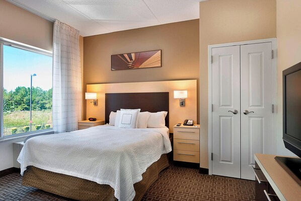 A hotel room with a bed, bedside lamps, a TV, and a wardrobe.