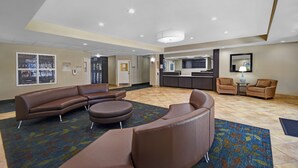 A spacious lobby with a curved brown sofa, a round ottoman, and two armchairs. - Candlewood Suites Sumter by IHG (Sumter)