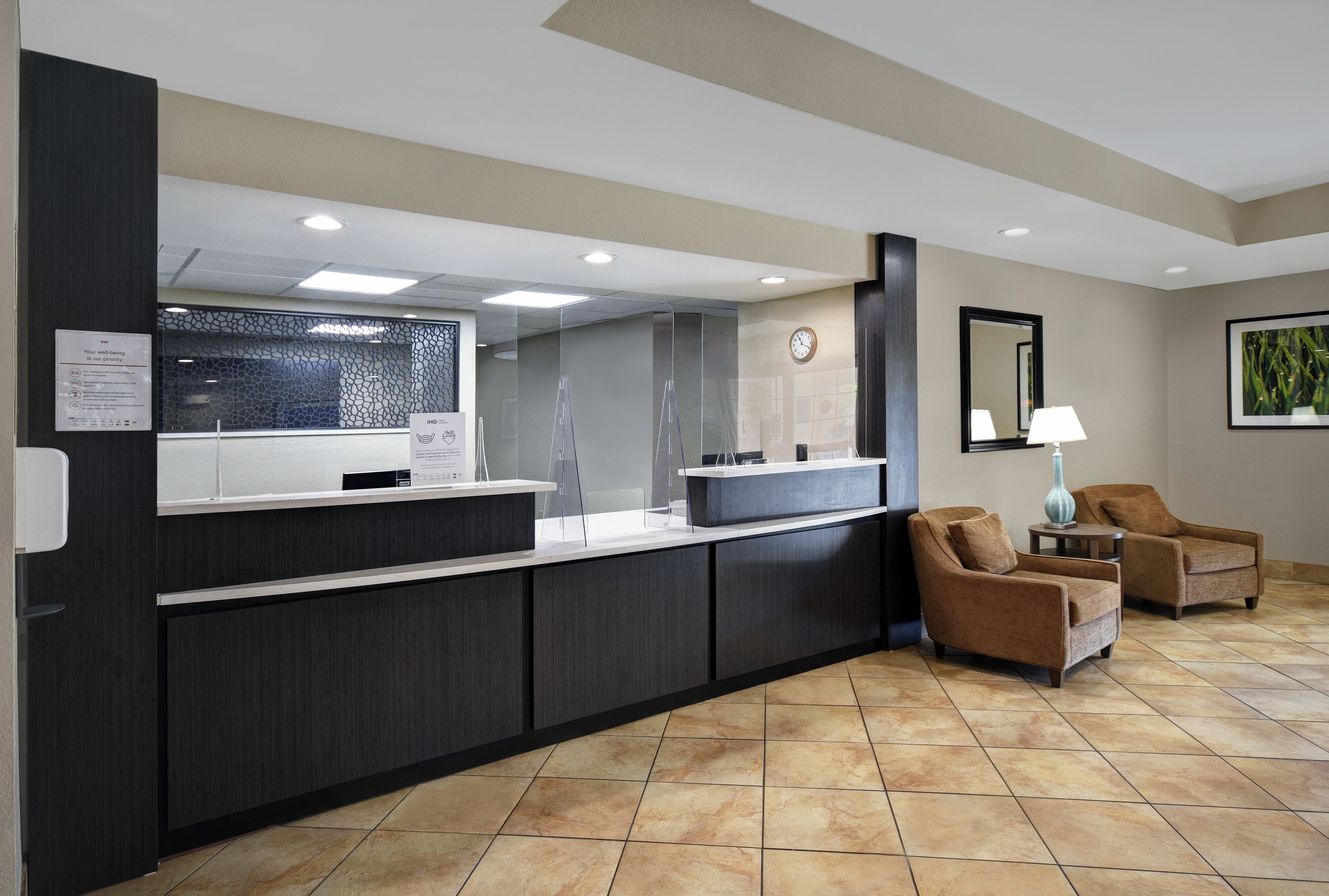 A reception area with a counter, chairs, a clock, and a framed picture on the wall.