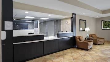 A reception area with a counter, chairs, a clock, and a framed picture on the wall.
