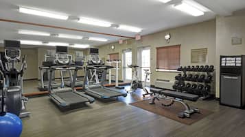 A gym with treadmills, stationary bikes, and a weight bench.