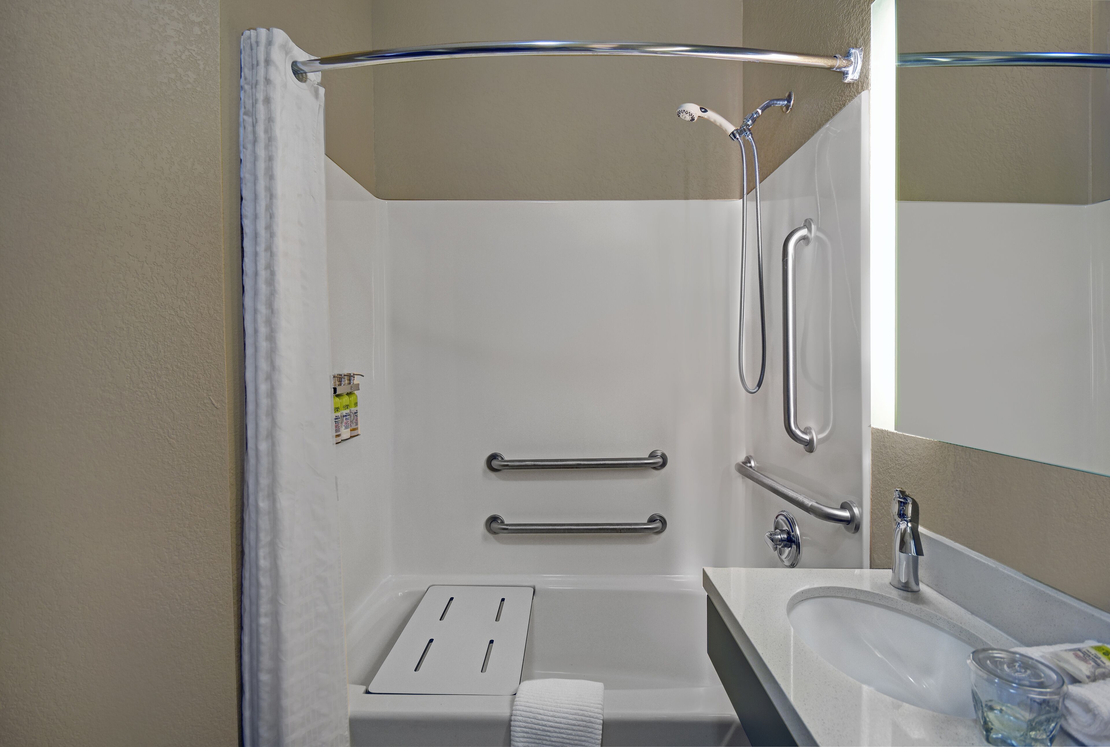 A modern bathroom with a shower, grab bars, a sink, and a towel rack.