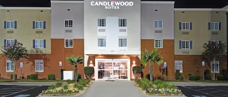 Entrada de hotel com uma placa indicando 'CANDLEWOOD SUITES' e um estacionamento na frente.