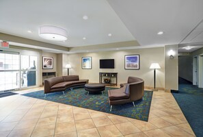 A hotel lobby with a seating area, a flat-screen TV, and a fireplace.