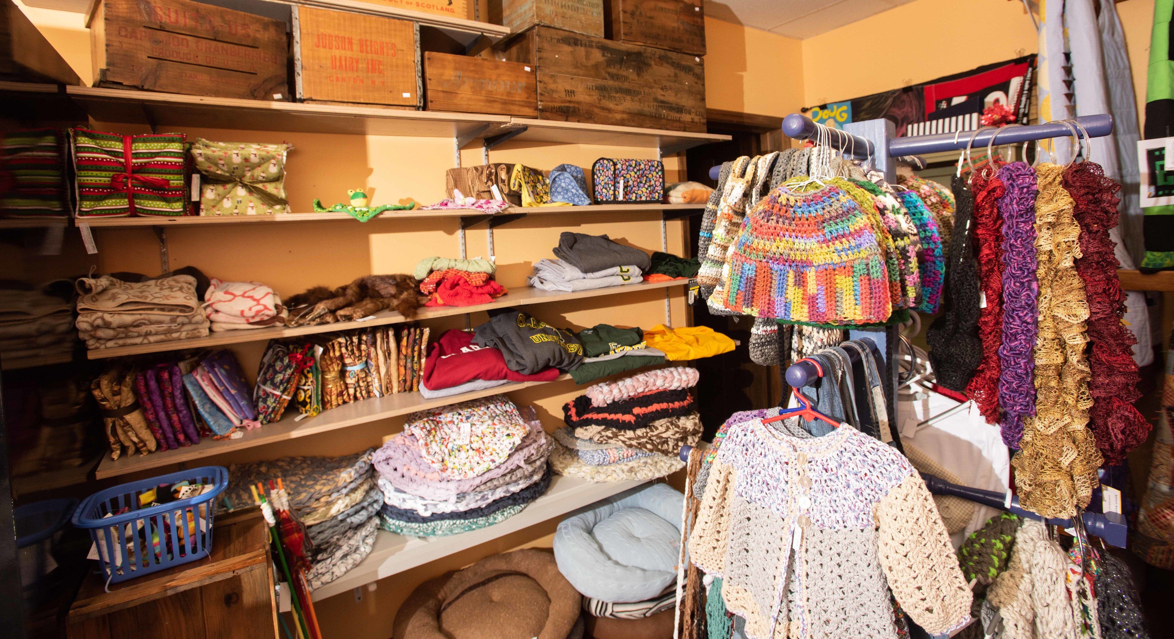 Une pièce de rangement avec des étagères remplies de divers objets, notamment des vêtements pliés, des chapeaux et des sacs.