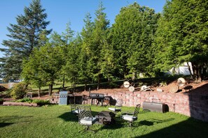 A backyard with a barbecue grill, outdoor furniture, and a brick wall. - Blue Spruce Motel (Massena)