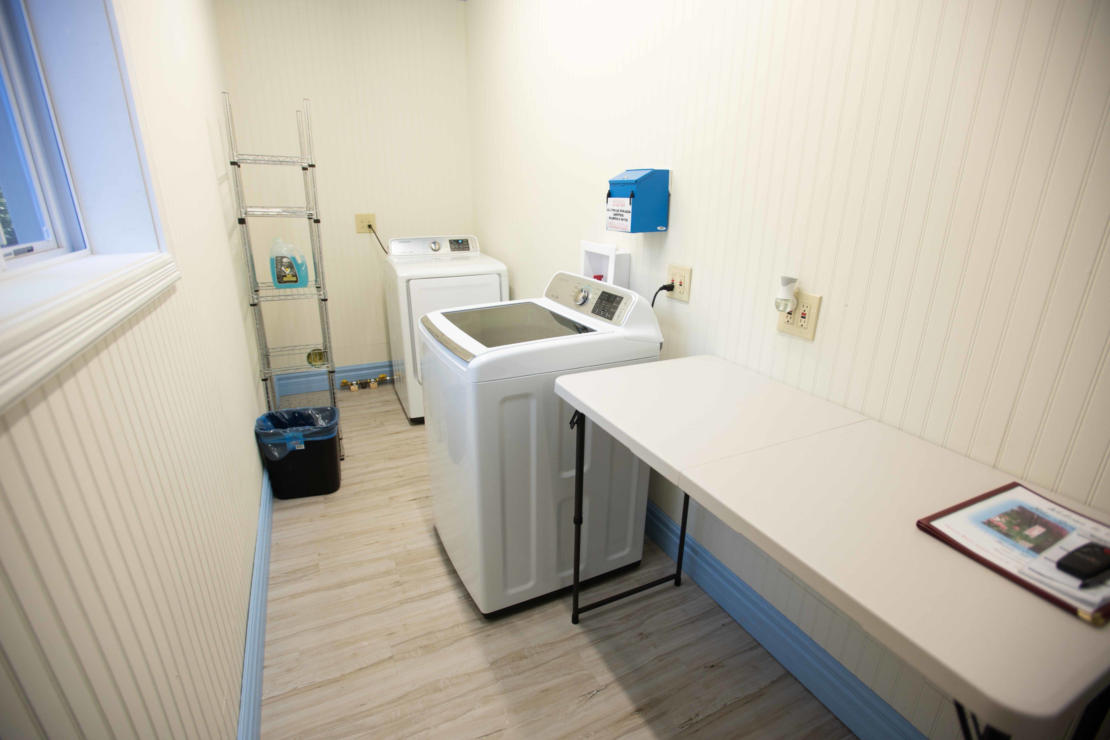 A laundry room with a washing machine, dryer, and a shelf with cleaning supplies.