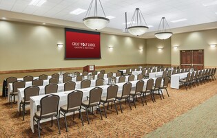 Un salón de conferencias con mesas largas y sillas, un cartel rojo con la inscripción 'Great Wolf Lodge Groups & Meetings' y suelo alfombrado.