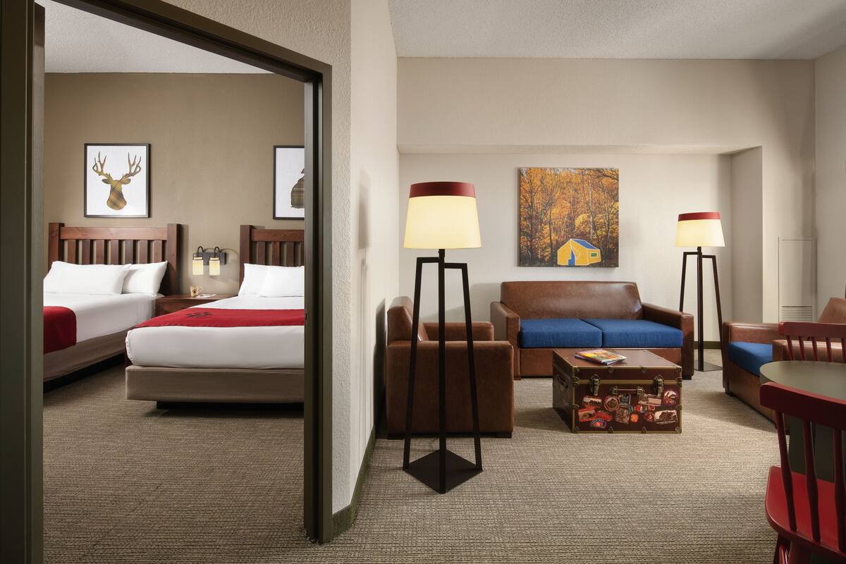 A hotel room with two beds, a sofa, a coffee table, and two floor lamps.