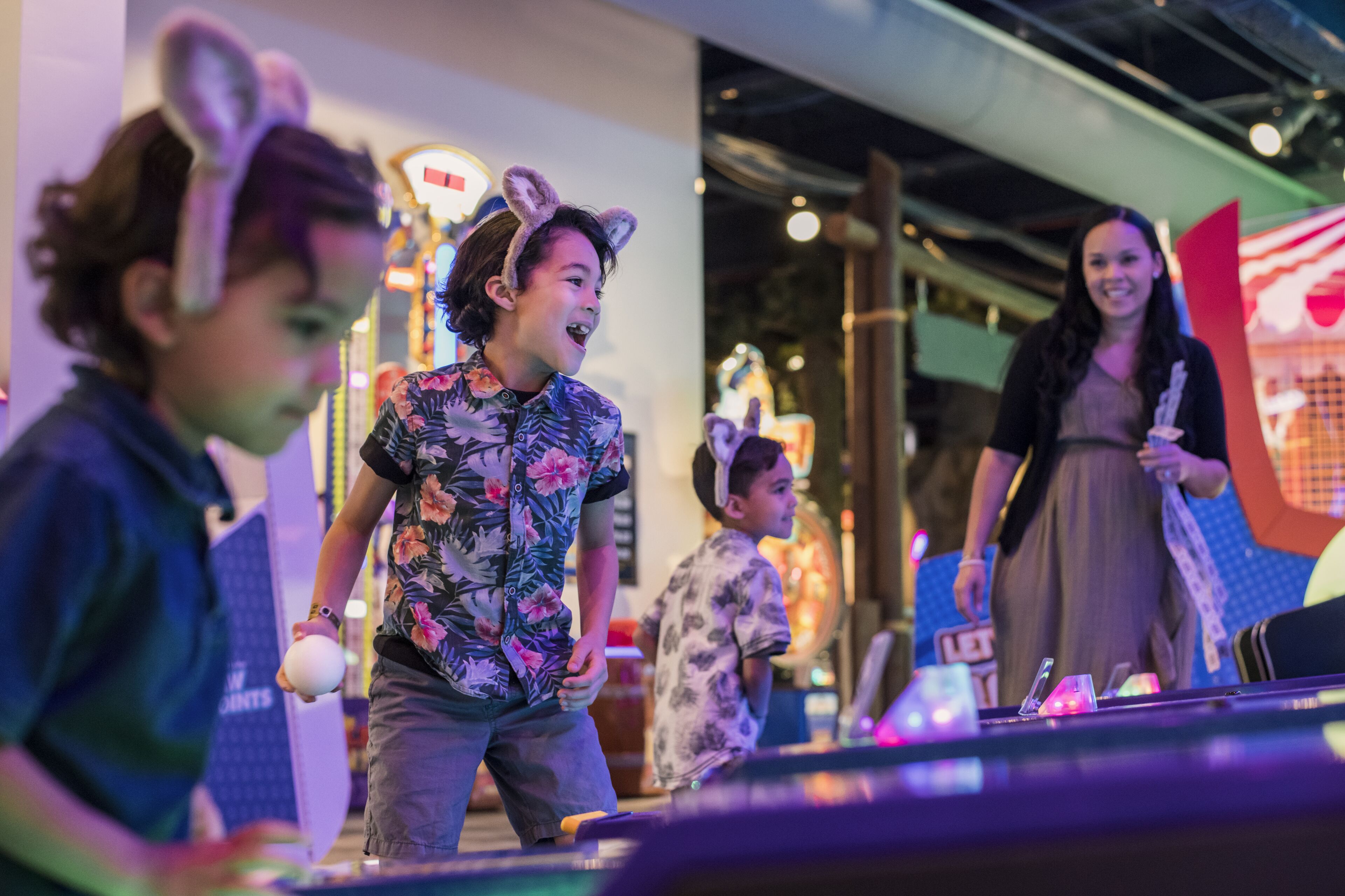 Un grupo de personas jugando a los bolos en un espacio interior, con un fondo bien iluminado y una pista de boliche visible.