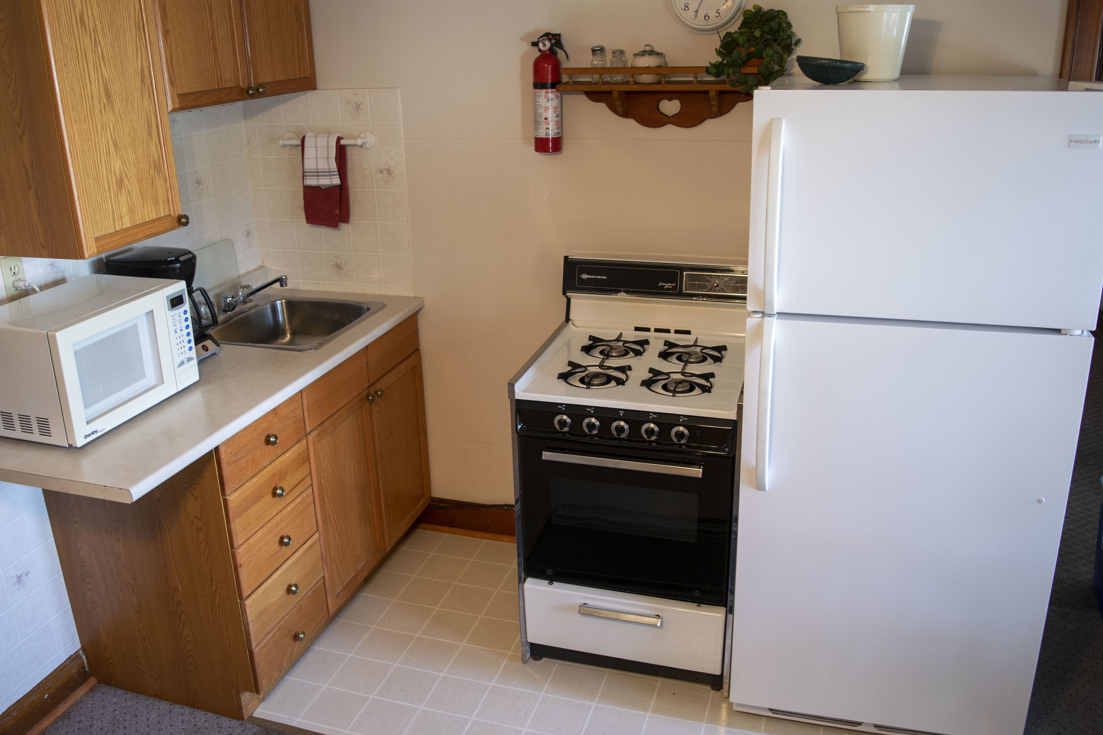A kitchen with a microwave, stove, sink, and refrigerator.