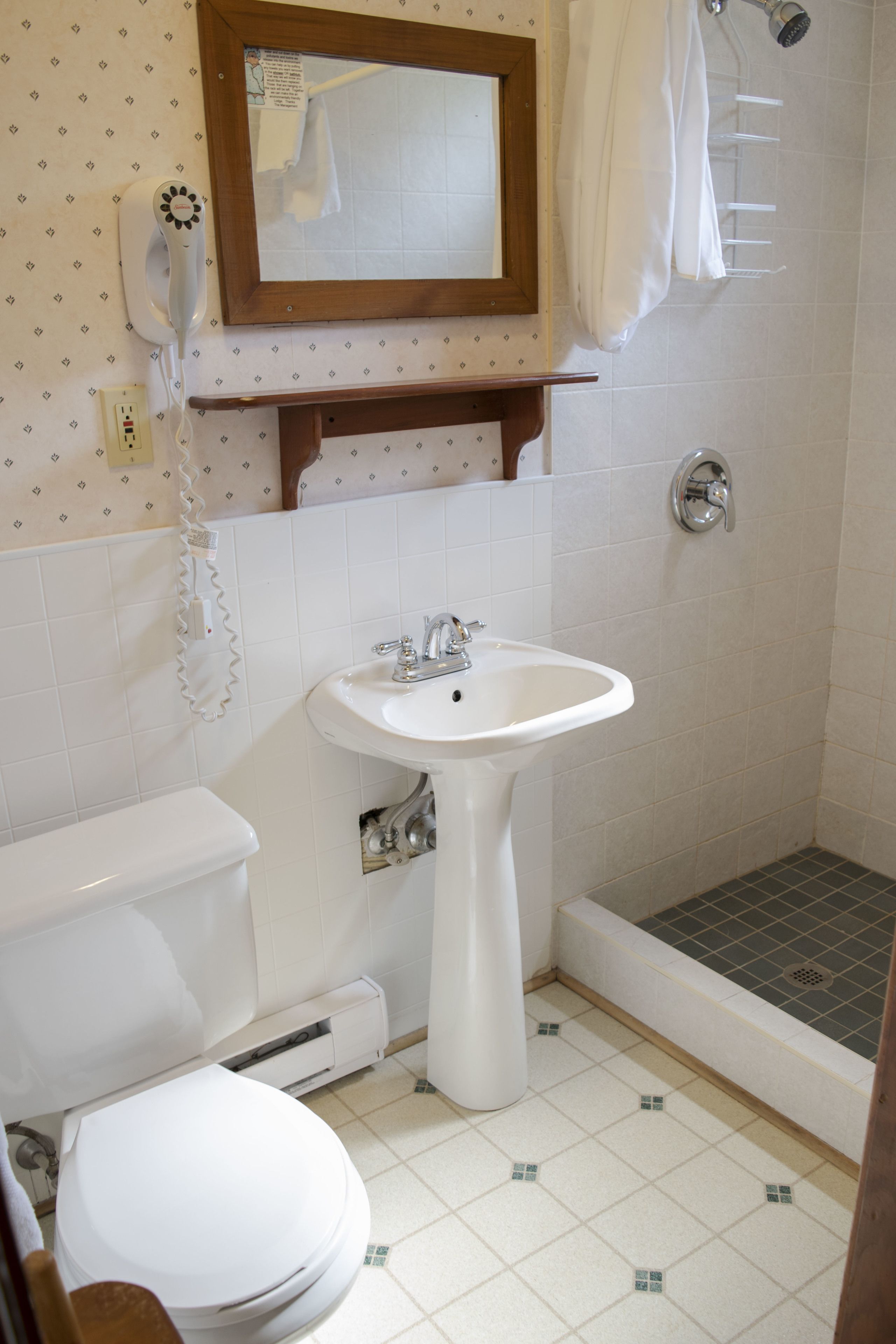 Un baño con inodoro, lavabo, ducha y un espejo sobre el lavabo.